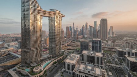 Téléchargez les photos : Futuriste Dubai Downtown et quartier financier skyline transition aérienne de nuit au jour. Nombreuses tours et gratte-ciel avec circulation dans les rues au lever du soleil avec reflets du soleil - en image libre de droit