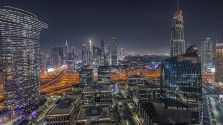 Foto de Panorama mostrando el futurista Dubai Downtown y la noche aérea del distrito financiero. Muchas torres iluminadas y rascacielos con tráfico en las calles - Imagen libre de derechos
