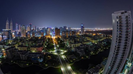 Foto de Panorama con rascacielos en el distrito de Barsha Heights y edificios de poca altura en la antena del distrito de Greens durante toda la noche. skyline de Dubai con el tráfico y las luces apagadas - Imagen libre de derechos