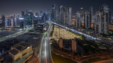 Photo for Panorama showing Bay Avenue with illuminated modern towers residential development in Business Bay aerial night, Dubai, UAE. Skyscrapers with traffic on a road near big parking lot - Royalty Free Image