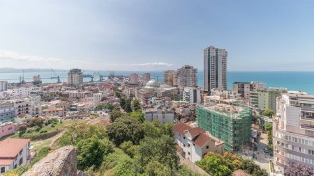 Photo for Panorama showing aerial view of city centre (old town) and the harbour of Durres timelapse from viewpoint, Albania. Many houses with green trees from above with clouds on she sky - Royalty Free Image
