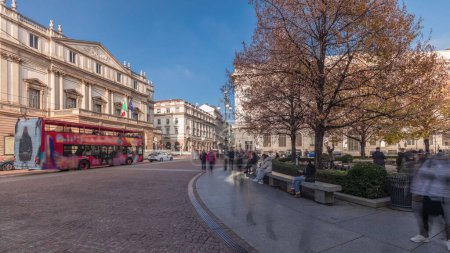 Foto de Panorama que muestra el teatro La Scala timelapse y un pequeño parque frente al edificio histórico con un monumento a Leonardo da Vinci y sus estudiantes. Gente caminando y sentada en un banco - Imagen libre de derechos