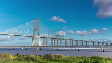 Foto de The Vasco da Gama Bridge timelapse hyperlapse. Cable-stayed longest bridge flanked by viaducts and rangeviews that spans the Tagus River in Park of Nations in Lisbon, the capital of Portugal - Imagen libre de derechos