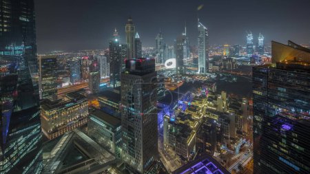 Foto de Panorama mostrando rascacielos futuristas en el centro de negocios del distrito financiero en Dubai en la noche de camino Sheikh Zayed. Vista aérea desde arriba con torres iluminadas - Imagen libre de derechos