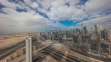 Foto de Skyline panorámico de Dubai con la bahía de negocios y el centro de la mañana distrito con largas sombras. Vista aérea de muchos rascacielos modernos con cielo azul nublado. Emiratos Árabes Unidos. - Imagen libre de derechos