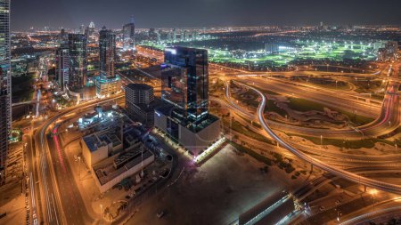Foto de Panorama que muestra el puerto deportivo de Dubái y los rascacielos iluminados JLT a lo largo de Sheikh Zayed Road con gran cruce y noche aérea del distrito de la ciudad de medios de comunicación. Edificios residenciales y de oficinas desde arriba. - Imagen libre de derechos