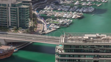 Photo for Aerial view to Dubai marina skyscrapers around canal with floating boats. White boats are parked in yacht club. Traffic on a bridge with moving shadows at morning - Royalty Free Image