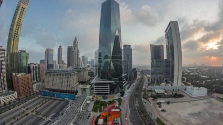 Photo for Panorama of Dubai International Financial district night to day transition. Aerial view of business office towers during sunrise. Illuminated skyscrapers with hotels and shopping malls near downtown - Royalty Free Image