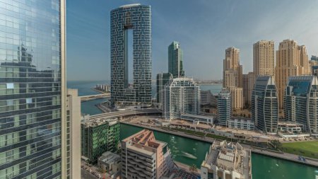 Téléchargez les photos : Panorama showing Dubai Marina with boats and yachts parked in harbor and skyscrapers around canal aerial morning during sunrise. Towers of JBR district on a background - en image libre de droit