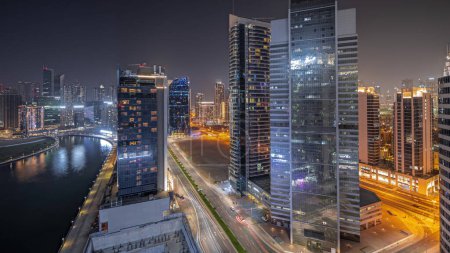 Téléchargez les photos : Panorama montrant le paysage urbain des gratte-ciel de Dubai Business Bay avec canal d'eau de nuit aérienne. Skyline moderne avec des tours éclairées et front de mer. Un centre d'affaires international - en image libre de droit
