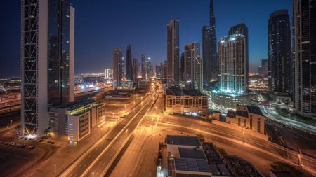 Photo for Aerial view of Dubai Downtown skyline with many towers night to day transition timelapse. Business area traffic in smart urban city. Skyscrapers and high-rise buildings from above before sunrise, UAE. - Royalty Free Image