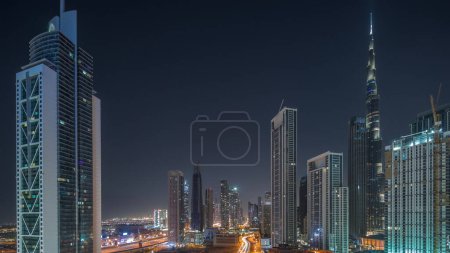 Foto de Vista aérea del horizonte del centro de Dubái con muchas de las torres iluminadas más altas durante toda la noche. Área de negocios en la ciudad urbana inteligente. Rascacielos y edificios de gran altura desde arriba, Emiratos Árabes Unidos. - Imagen libre de derechos