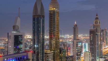 Téléchargez les photos : Vue aérienne des immeubles de grande hauteur sur Sheikh Zayed Road à Dubaï, de nuit aérienne à jour Timelapse transition, EAU. Les gratte-ciel de la place financière internationale d'en haut avant le lever du soleil - en image libre de droit