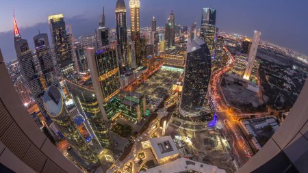 Téléchargez les photos : Skyline panorama des immeubles de grande hauteur sur Sheikh Zayed Road à Dubaï passage aérien du jour à la nuit timelapse, EAU. Des gratte-ciel éclairés de la place financière internationale d'en haut - en image libre de droit