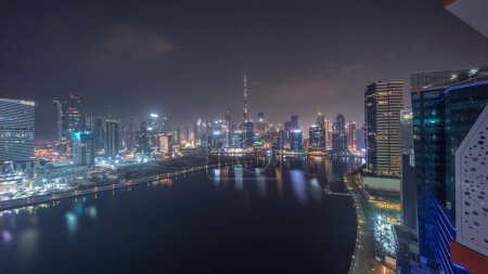 Foto de Vista panorámica aérea de Dubai Business Bay y el centro de la ciudad con los diversos rascacielos y torres a lo largo de la costa en la noche del canal timelapse durante toda la noche. Construcción con grúas - Imagen libre de derechos