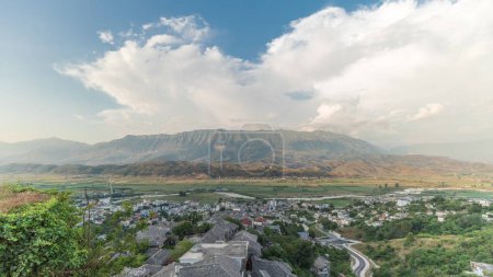 Téléchargez les photos : Panorama montrant la ville de Gjirokastra du point de vue de la forteresse du château ottoman de Gjirokaster timelapse. Albanie vue aérienne sur la vallée et les montagnes pendant l'heure du coucher du soleil - en image libre de droit