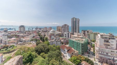 Photo for Panorama showing aerial view of city center (old town) and the harbor of Durres timelapse from viewpoint, Albania. Many houses with green trees from above with clouds on she sky - Royalty Free Image