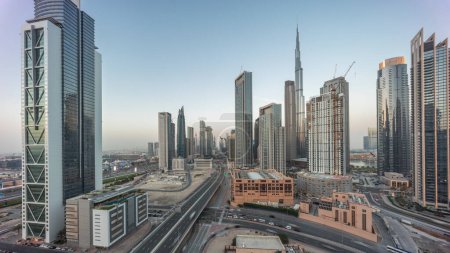Foto de Vista panorámica aérea del horizonte del centro de Dubái con muchas torres de día a noche timelapse transición. Área de negocios en la ciudad urbana inteligente. Rascacielos y edificios de gran altura desde arriba después del atardecer, EAU. - Imagen libre de derechos