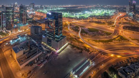 Photo for Huge highway crossroad junction between JLT district and media city intersected by Sheikh Zayed Road aerial night after sunset. Golf course near towers and skyscrapers with busy traffic - Royalty Free Image