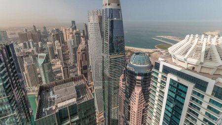 Téléchargez les photos : Panorama montrant Dubai Marina et JLT avec quartier JBR le matin. Circulation sur l'autoroute entre les gratte-ciel timelapse aérien. Tours modernes et chantier de construction. Yachts flottant dans le port - en image libre de droit