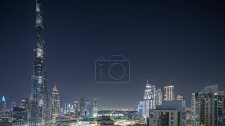 Téléchargez les photos : Panorama montrant le paysage urbain aérien de nuit timelapse avec l'architecture illuminée du centre-ville de Dubaï. Beaucoup de grands gratte-ciel et des tours avec des fenêtres éclatantes. Nouveau chantier de construction. - en image libre de droit