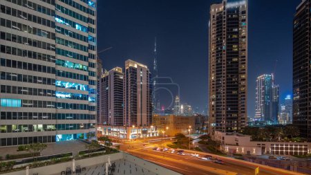 Téléchargez les photos : Vue panoramique aérienne du centre-ville de Dubaï et des gratte-ciels difc avec un trafic achalandé à l'intersection dans le quartier de Business Bay, du jour à la nuit.. - en image libre de droit
