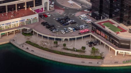 Téléchargez les photos : Parking au bord de l'eau vue de dessus timelapse pendant toute la journée, vue aérienne. Vue de dessus des véhicules stationnés près de l'immeuble de bureaux dans le quartier JLT de Dubaï. Ombres se déplaçant rapidement - en image libre de droit