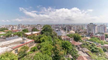 Photo for Panorama showing aerial view of city center (old town) and the harbor of Durres timelapse from viewpoint, Albania. Many houses with red roofs and green trees from above with clouds on she sky - Royalty Free Image