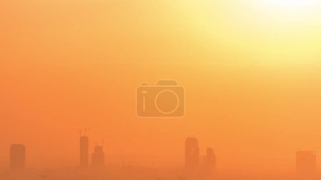 Foto de Salida del sol sobre los verdes y al barsha alturas distrito timelapse aéreo de Dubai marina. Sol saliendo detrás de torres y rascacielos cerca del campo de golf desde arriba - Imagen libre de derechos