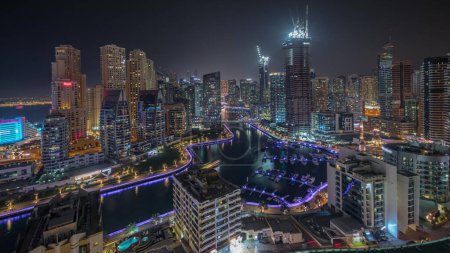Foto de Panorama que muestra los rascacielos Dubai Marina y el distrito JBR con edificios de lujo y resorts de noche aérea timelapse. Frente al mar iluminado y barcos flotando en el canal - Imagen libre de derechos