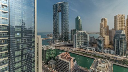Téléchargez les photos : Panorama montrant Dubai Marina avec bateaux et yachts garés dans le port et gratte-ciel autour du canal matin aérien timelapse pendant le lever du soleil. Tours du quartier JBR sur fond - en image libre de droit