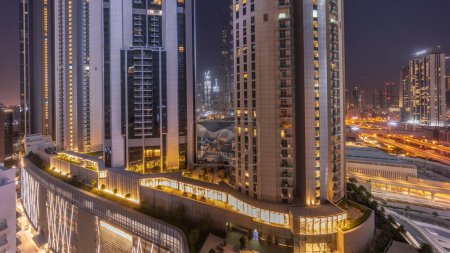 Foto de Los rascacielos más altos del centro de Dubái se encuentran en la calle Boulevard, cerca del centro comercial Timelapse aéreo durante toda la noche y la puesta de Luna. Zona de paseo con jardines en la azotea - Imagen libre de derechos