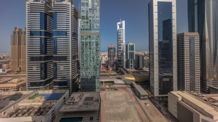 Téléchargez les photos : Vue aérienne du lever du soleil du quartier financier international de Dubaï avec de nombreux gratte-ciel timelapse. Trafic sur une route près de bâtiments à plusieurs étages avec de longues ombres le matin. Dubai, Émirats arabes unis. - en image libre de droit