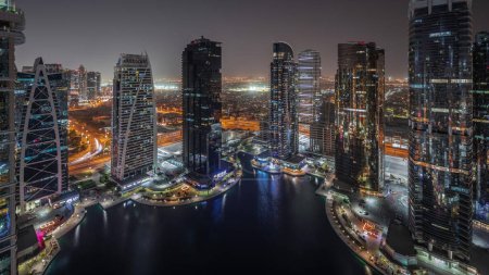 Foto de Panorama que muestra edificios residenciales altos en el timelapse aéreo nocturno del distrito JLT, parte del distrito de uso mixto del centro de productos básicos de Dubai. Torres y rascacielos iluminados - Imagen libre de derechos