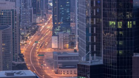 Téléchargez les photos : Vue aérienne d'en haut à des intersections animées à Dubaï, nuit à jour, période de transition. Voitures conduisant directement dans les deux sens de la route avant le lever du soleil. Quartier des affaires gratte-ciel - en image libre de droit