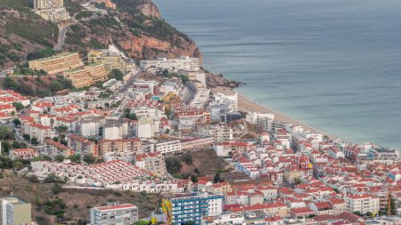 Photo for Aerial view of the coastline of the village of Sesimbra timelapse, in the middle of the Atlantic Ocean. Evening time with typical houses from the Castle viewpoint. Portugal - Royalty Free Image