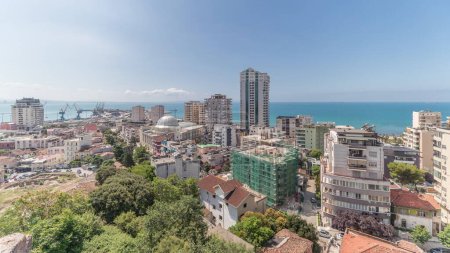 Photo for Panorama showing aerial view of city center (old town) and the harbor of Durres timelapse from viewpoint, Albania. Many houses with green trees from above with clouds on she sky - Royalty Free Image