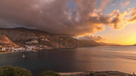 Foto de Panorama mostrando nubes naranjas durante el atardecer en el timelapse aéreo de la isla de Amorgos desde arriba. Grecia tradicional - casas blancas en colinas y mar turquesa, Cícladas - Imagen libre de derechos