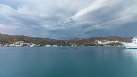 Photo for Panorama showing Amorgos island timelapse at evening during sunset. Traditional Greece - white houses on hills and ship in sea port in harbor, Cyclades - Royalty Free Image