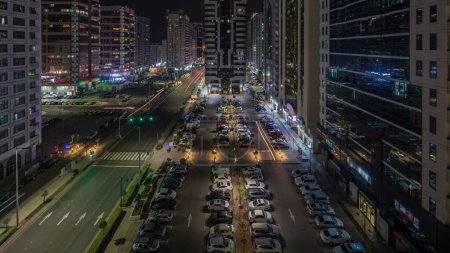 Téléchargez les photos : Bâtiments résidentiels et architecture moderne de la ville d'Abu Dhabi timelapse aérien pendant toute la nuit, EAU. Vue d'en haut pour les voitures sur le parking et les tours avec gratte-ciel aux Émirats Arabes Unis - en image libre de droit