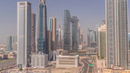 Foto de Torres futuristas y rascacielos con tráfico en las calles del centro de Dubái y el distrito financiero durante todo el día. Ciudad urbana horizonte timelapse aéreo con sombras que se mueven rápido hasta el atardecer - Imagen libre de derechos