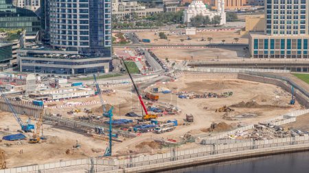 Foto de Conducción de pilotes en foso de cimentación para la construcción del edificio de apartamentos timelapse aéreo. Instalación profunda y excavación con excavadoras, grúas, bulldozers y camiones, Dubai business bay - Imagen libre de derechos