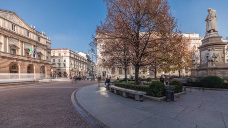 Téléchargez les photos : Panorama showing theater La Scala timelapse and a small park opposite to historic building with a monument to Leonardo da Vinci and his students. People walking around and sitting on a bench - en image libre de droit