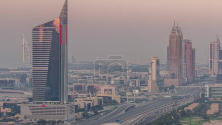 Foto de Vista aérea de Sheikh Zayed Road en Dubai Internet City área timelapse. Rascacielos y tráfico en una carretera con estación de metro al atardecer - Imagen libre de derechos