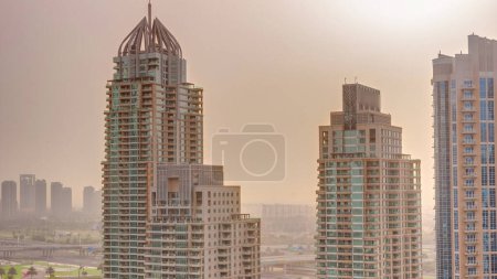 Foto de Salida del sol sobre Dubai Marina distrito turístico de lujo con rascacielos y torres alrededor del canal timelapse aéreo. Edificios residenciales y tráfico en las calles. Nubes naranjas - Imagen libre de derechos