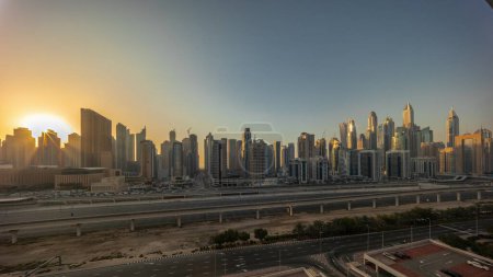 Téléchargez les photos : Dubai Marina plus haut bloc de gratte-ciel timelapse pendant toute la journée avec des ombres se déplaçant rapidement. Vue panoramique aérienne du quartier JLT vers les immeubles d'appartements, les hôtels et les tours de bureaux près de l'autoroute. - en image libre de droit