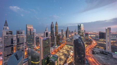 Foto de Vista panorámica del horizonte de los edificios de gran altura en Sheikh Zayed Road en Dubai noche aérea al día timelapse transición, Emiratos Árabes Unidos. Rascacielos en el Centro Financiero Internacional desde arriba antes del amanecer - Imagen libre de derechos