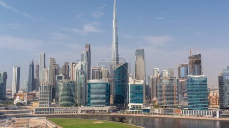 Foto de Vista aérea de Dubai Business Bay y el centro de la ciudad con los diversos rascacielos y torres a lo largo de la costa en el timelapse canal. Planta de construcción con grúas. Las sombras se mueven rápido - Imagen libre de derechos