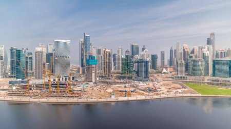 Foto de Panorama del paisaje urbano con rascacielos de Dubai Business Bay y timelapse aéreo del canal de agua. skyline moderno con torres residenciales y de oficina en el paseo marítimo. Grúas en una obra de construcción de un nuevo bloque - Imagen libre de derechos