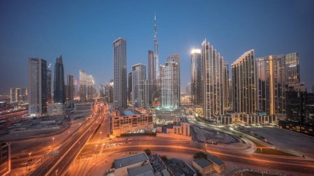 Téléchargez les photos : Vue aérienne panoramique de Dubaï Skyline du centre-ville avec de nombreuses tours timelapse de transition de jour à nuit. Zone d'affaires trafic routier achalandé. gratte-ciel et gratte-ciel d'en haut après le coucher du soleil, Émirats arabes unis - en image libre de droit